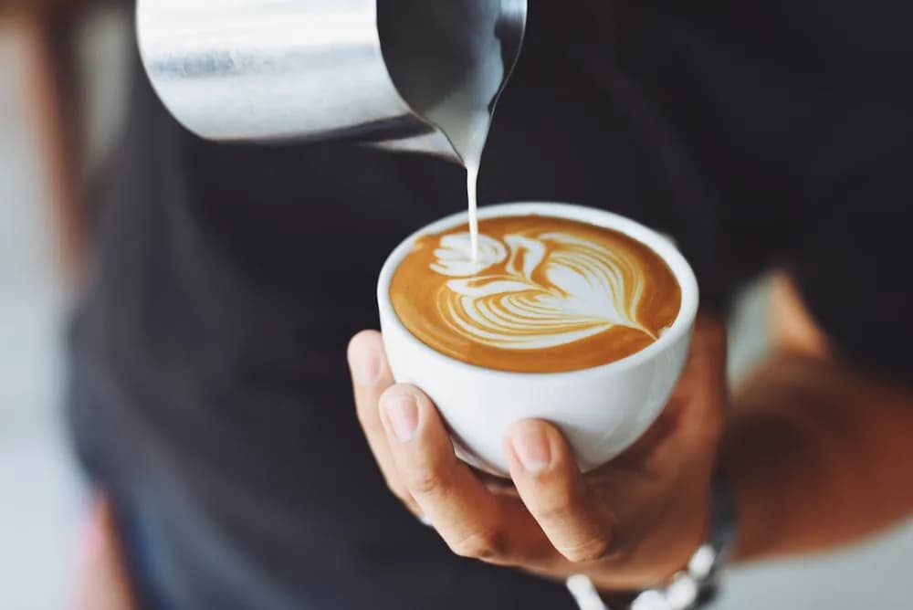 Un barista verse délicatement un latte art